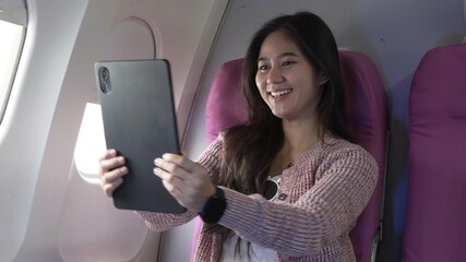 A lovely Asian businesswoman sits at the airplane window, working with a laptop and holding a smartphone confidently,demonstrating her efficiency,professionalism and modern travel lifestyle on board - Powered by Adobe