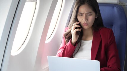 A lovely Asian businesswoman sits at the airplane window, working with a laptop and holding a smartphone confidently,demonstrating her efficiency,professionalism and modern travel lifestyle on board - Powered by Adobe