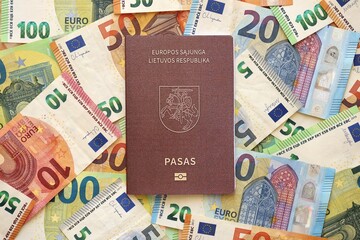 Lithuania passport lies on big amount of euro money banknotes. Rich life and travel in Europe