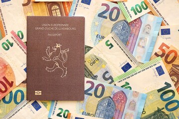 Luxembourg passport lies on big amount of euro money banknotes. Rich life and travel in Europe