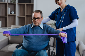 A white female nurse is assisting an elderly male patient with crutches, helping him get up from a...