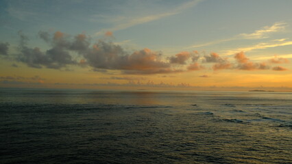 A peaceful scene of the calm sea stretching to the horizon under a sky with soft, pastel-colored...