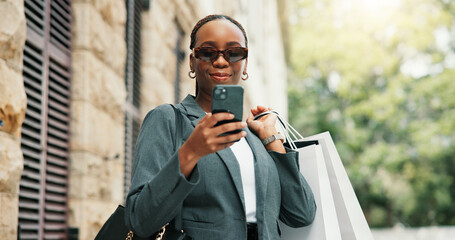 Shopping bags, cellphone and black woman in city, sunglasses and mobile app with commute. Outdoor,...