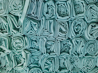 A stack of colorful hijabs or headscarves neatly folded into a square roll. A head covering for Muslim women.