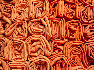 A stack of colorful hijabs or headscarves neatly folded into a square roll. A head covering for...