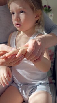 Mother applying moisturizing cream to child s hands and feet in soft natural light. Gentle skincare routine, parent-child bonding, and healthy skin protection. Close-up, warm atmosphere, self-care