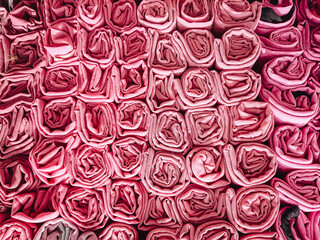 A stack of colorful hijabs or headscarves neatly folded into a square roll. A head covering for...