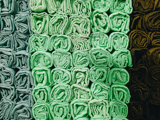 A stack of colorful hijabs or headscarves neatly folded into a square roll. A head covering for...