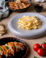 This image, featuring fresh pasta garnished with grated cheese, grilled chicken, and rich sauces, is perfect for a delicious lunch or dinner menu. It's an ideal stock photo for cookbooks, blogs, menus