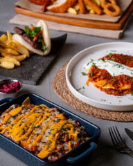  This photo, filled with nachos covered in melted cheese sauce, a red meat wrap, and crispy french fries, is appealing to those who love American-style food. It's a great choice for fast food-themed 
