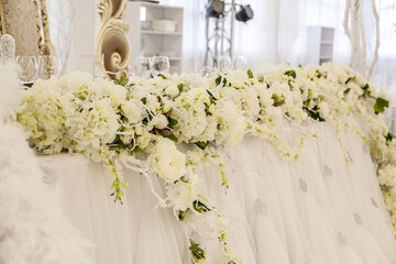 Beautiful floral decoration on a wedding reception table with elegant white drapes