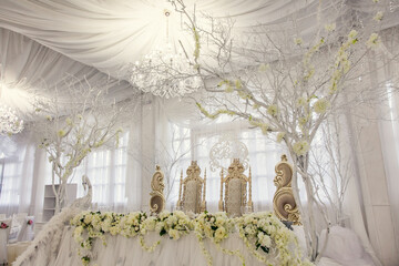 Elegant wedding decoration featuring floral arrangements and ornate chairs in a bright venue