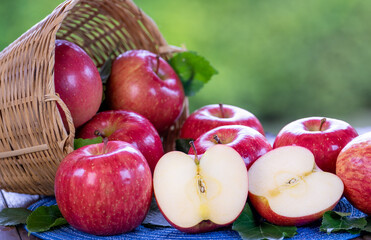 Red Applw on green nature bokeh background. Many Red apples in basket on wooden table.