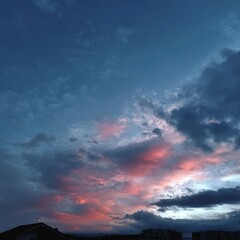 Obraz premium Beautiful sunset casting pink and purple hues across the sky in a quiet town during evening hours