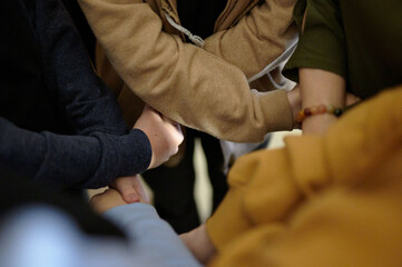 Close-up of a group of hands, one adult and multiple children, clasped together, symbolizing unity...