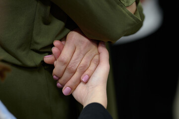 A close-up of two hands, one adult and one child, clasped together, illustrating care, protection, and nurturing