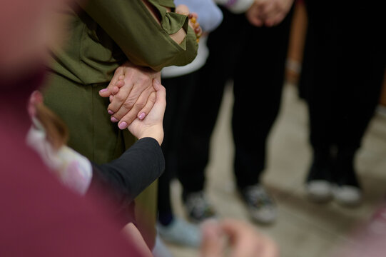 Close-up of a hand in a supporting gesture, surrounded by others, demonstrating support, unity, and care within a community