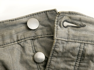 Close up of gray denim jeans waistband with metal buttons and buttonhole