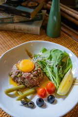 Exquisite Culinary Creation: A gourmet steak tartare is exquisitely presented on a pristine white plate, adorned with fresh, vibrant garnishes, celebrating the art of fine dining.