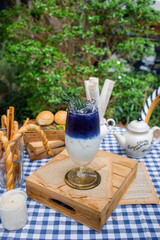 Elegant drink Delight in Garden: A visually stunning, layered cocktail graces a garden-set table, accompanied by rustic breadsticks and rolls.