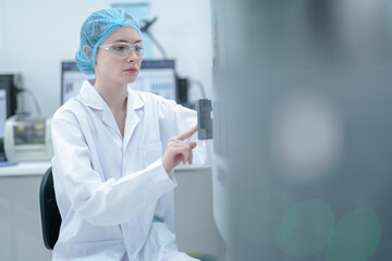 A laboratory professional wearing a hair net and safety glasses loads a sample tray into an automated clinical analyzer, preparing for a series of medical tests in a modern facility.