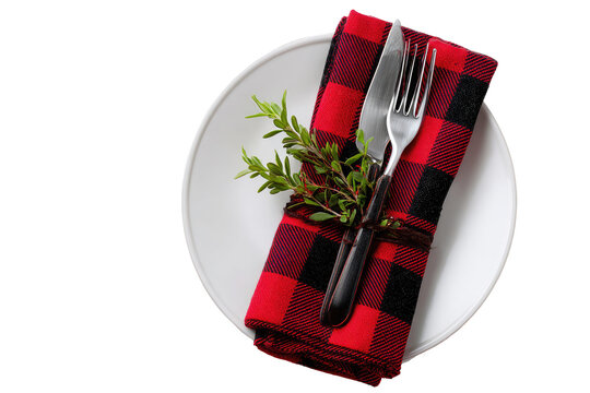 Festive table setting with red and black checkered napkin, cutlery, and herbs