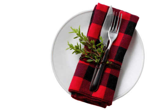 Festive table setting with red and black checkered napkin, cutlery, and herbs