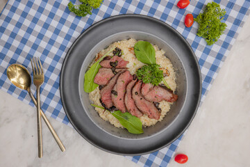 Gourmet Plate: A delectable dish of seasoned meat, meticulously arranged atop a bed of grains. Embellished with herbs and accents, it's a testament to culinary artistry and flavor