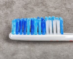 Close-up of a used toothbrush head with blue and white bristles