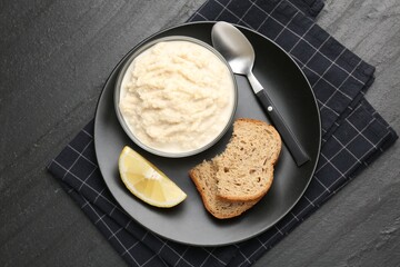 Tasty horseradish sauce served on black table, top view