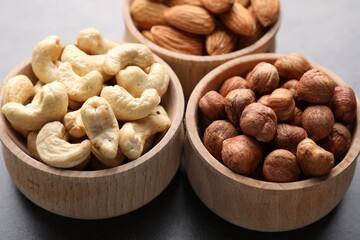 Different nuts in bowls on grey table, closeup