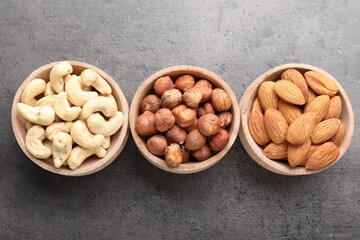 Different nuts in bowls on grey table, flat lay