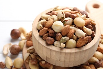 Mix of different nuts in bowl on white table, closeup