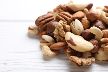 Mix of different nuts on white wooden table, closeup. Space for text