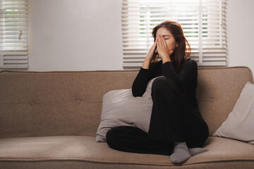 Obraz premium Sad woman experiencing grief, loneliness, and mental health issues sitting on her sofa at home