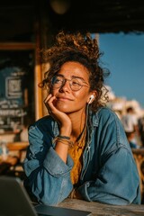 Fototapeta premium Young woman working on laptop in cafe during sunset