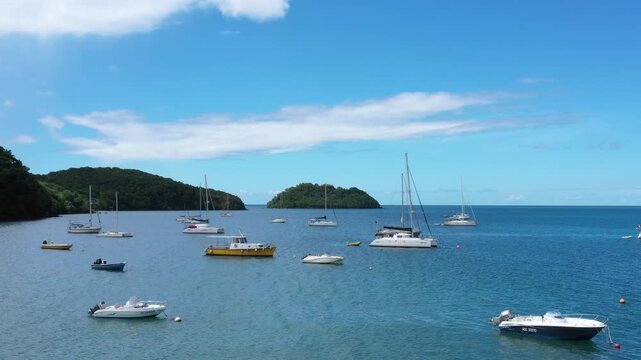 Sailboats anchored near islet Ramier in Martinique with blue sea, sky and lush green islands