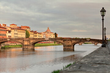 Ponte Santa Trinita Bridge east side at sunrise under a colorful cloudy sky, seen westward from Lungarno degli Acciaiuoli Road. Florence-Tuscany-329