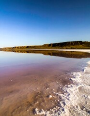 Calm pink lake reflecting a clear blue sky