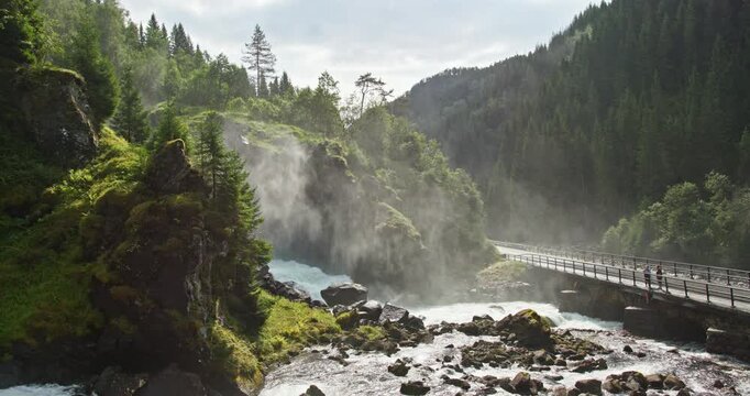 Latefossen waterfall, stone arch bridge and mist over mountain road, Norway
