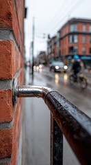 Close-up of a metal railing next to a brick wall on a rainy city street