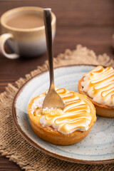 French lemon tart with meringue on brown wooden, linen textile, side view, close up, selective focus