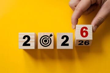 A hand places the final wooden cube with the number six on it to complete the year 2026 symbolizing future goals and planning