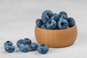Fresh ripe blueberries in small wooden bowl on gray textured stone background. Delicious organic fruit rich in vitamins, wild berries,healthy lifestyle, natural food. Close up, macro
