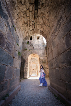Asian woman tourist take a holiday for travel in summer at Acropolis of Pergamon Ancient Greek City, Landmark of Tourism Turkiye, Izmir, Turkey. She is standing archway area and enjoy relax vacation.