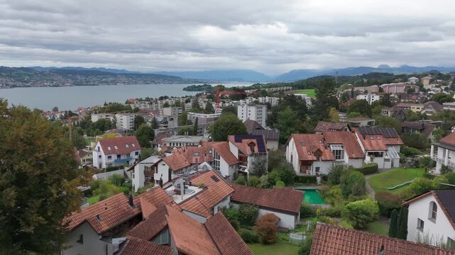 Forward drone over Horgen on Lake Zurich, showing rooftops, lakeshore and distant Alps.