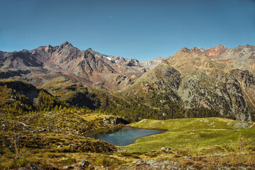 Mountain lake in the Ultental near Bolzano and Merano, South Tyrol, Italy, captured from an alternative angle, showing alpine peaks, serene water, and a clear blue sky