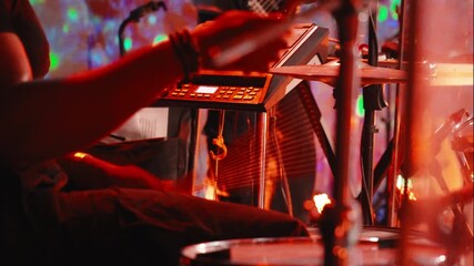 Stage red lights highlighting musician playing electronic drum pad, generating dynamic worship atmosphere with intense musical energy during christian praise event