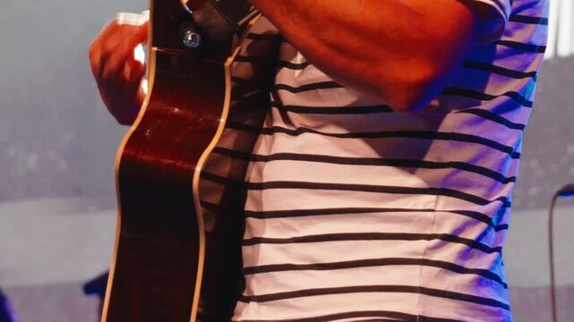 Musician playing acoustic guitar, performing passionate worship song with heartfelt energy during church service, hands moving across strings