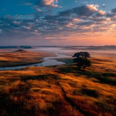 Fototapeta premium Golden hour landscape with winding river, misty valley, and dramatic sunset sky, peaceful scenery